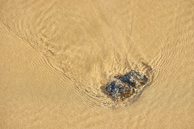 Brown sand with water during the day
